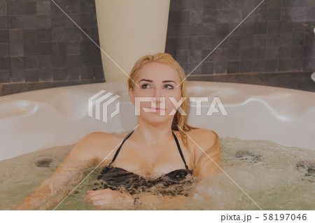 Young beautiful woman relaxes in a jacuzzi. Young beautiful woman relaxes in a jacuzzi. 58197046
