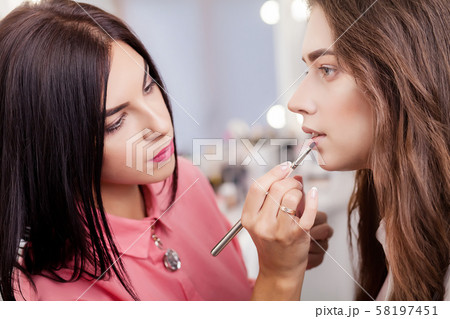 Make-up artist does makeup to a beautiful girl in a beauty salon Make-up artist does makeup to a beautiful girl in a beauty salon 58197451