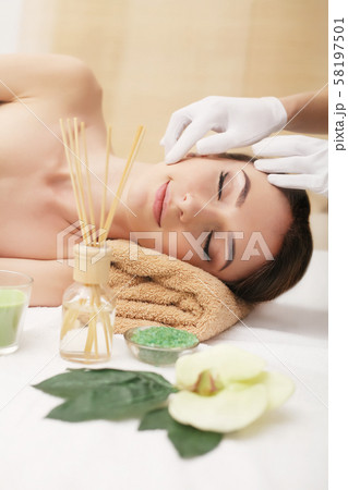 Beautiful young woman getting facial massage lying on the couch. Top view focused on the face 58197501