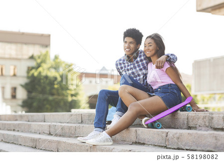 Couple of teenagers sitting on stairs outdoors 58198082