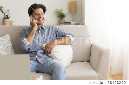 Positive Man Talking By Cellphone Sitting On Couch At Home 58198290