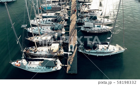 Low altitude aerial down view of a marina pier and many docked sailing yachts Low altitude aerial down view of a marina pier and many docked sailing yachts 58198332