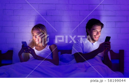 Young Spouses Using Phones Lying In Bed At Night Young Spouses Using Phones Lying In Bed At Night 58199044