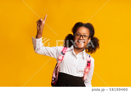 African American Schoolgirl Pointing Finger Up On Yellow Background 58199460