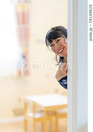部屋の陰から顔を出す可愛い女の子の写真素材