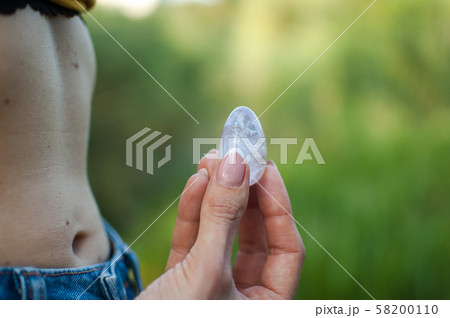 Side view of adult woman holding transparent violet amethyst yoni egg for vumfit, imbuilding or 58200110
