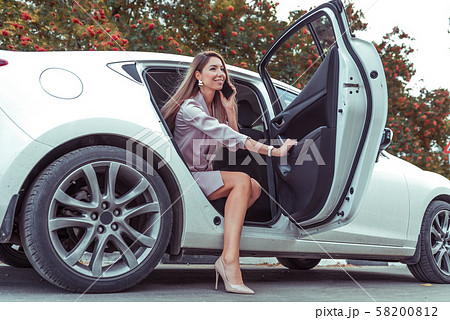 Happy beautiful woman calling phone, getting out car business sedan VIP class taxi, summer spring 58200812