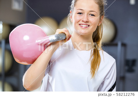 Young cheerful woman holds kettlebell at fitness gym center Young cheerful woman holds kettlebell at fitness gym center 58212276