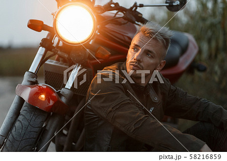 Brutal man in a military jacket sits and resting 58216859