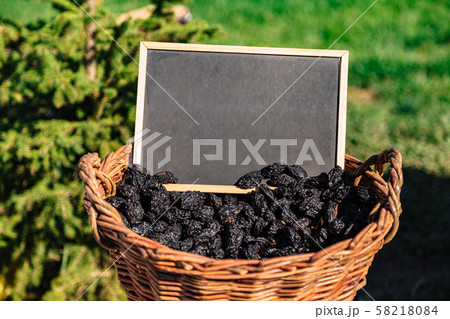 Basket full of oval shaped black prunes on field Basket full of oval shaped black prunes on field 58218084