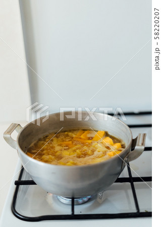 Pumpkin soup cooking in sausepan in the kitchen on the stove. Autumn traditional food Pumpkin soup cooking in sausepan in the kitchen on the stove. Autumn traditional food 58220207
