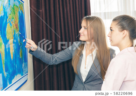 Two business-like young women plot a route on a 58220696