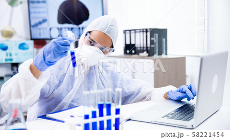 Caucasian scientist analyzes the tube and make some notes on laptop 58221454