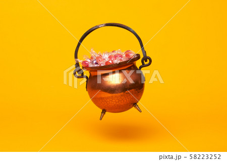 Iron pot with multi-colored sweets on orange background 58223252
