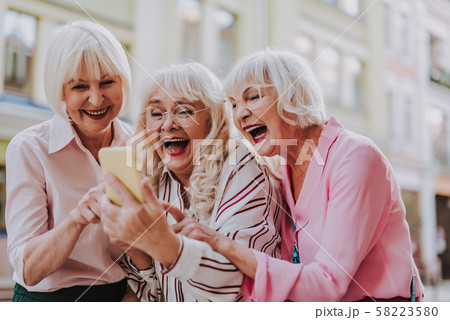 Three old females looking at the phone and laughing Three old females looking at the phone and laughing 58223580