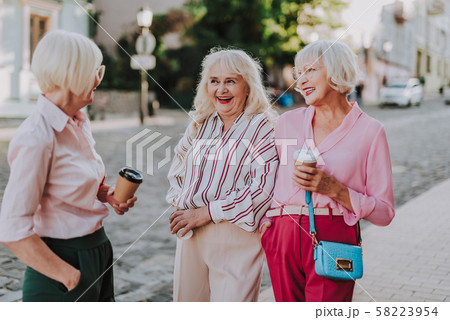 Three smiling elderly women are communicating on road 58223954