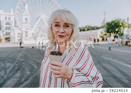 Beautiful mature woman is drinking coffee on square Beautiful mature woman is drinking coffee on square 58224014