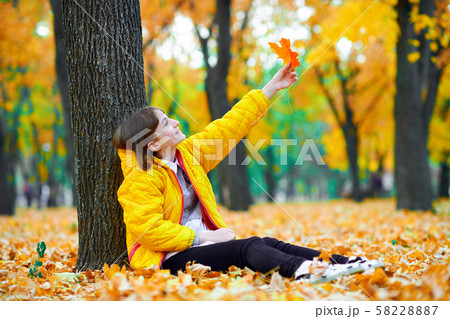teen girl sitting with autumn leaves in city park, teen girl sitting with autumn leaves in city park, 58228887