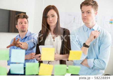 Businesswoman Looking At Strategies On Adhesive Notes By Colleag 58228894