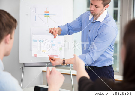 Businessman Showing Chart To Colleagues In Office 58229353