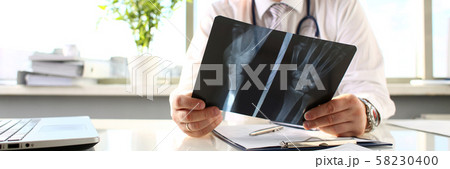 Male doctor hold in arm silver pen and look at xray Male doctor hold in arm silver pen and look at xray 58230400