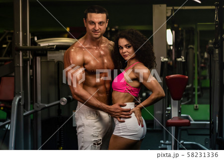 sportive muscular man and woman in gym. couple in gym . sportive muscular man and woman in gym. couple in gym . 58231336