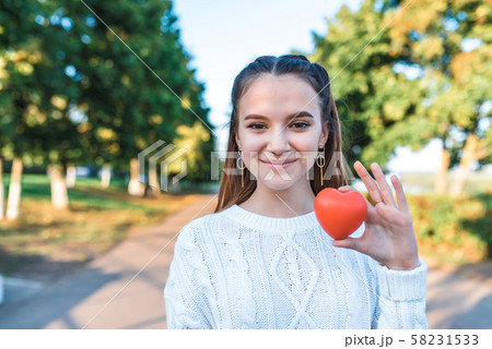 Happy cheerful teenage girl 13-15 years old, summer autumn spring in park, red heart in her hand Happy cheerful teenage girl 13-15 years old, summer autumn spring in park, red heart in her hand 58231533