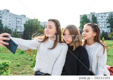 Teenage girls in summer autumn spring in city, take pictures on smartphone, on-line application on Teenage girls in summer autumn spring in city, take pictures on smartphone, on-line application on 58231563