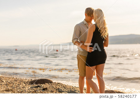 Beautiful young couple in romantic embrace on beach at summer Beautiful young couple in romantic embrace on beach at summer 58240177