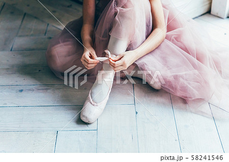 Ballerina hands puts pointe shoes on leg in dance 58241546