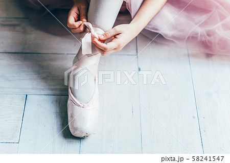 Ballerina hands puts pointe shoes on leg in dance 58241547