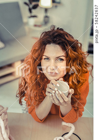 Kind cute girl leaning her elbows on a table 58242637