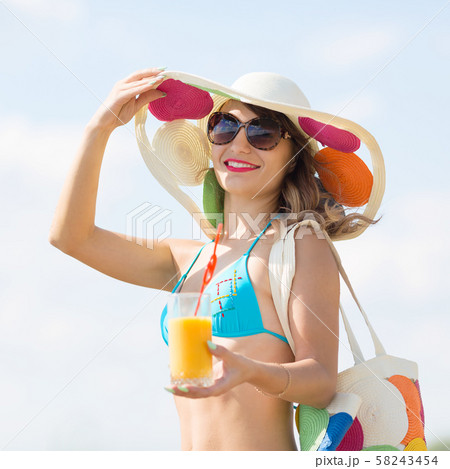 A girl stands by the sea with a glass of juice. A girl stands by the sea with a glass of juice. 58243454