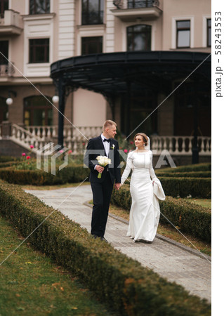 Stylish couple walking in the park at their wedding day. Happy newlyweds outside in autumn weather 58243553