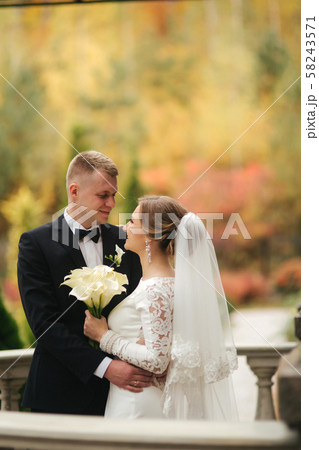 Portrait of beautiful wedding couple stand on the balcony. Stylish bride and groom in autumn weather Portrait of beautiful wedding couple stand on the balcony. Stylish bride and groom in autumn weather 58243571