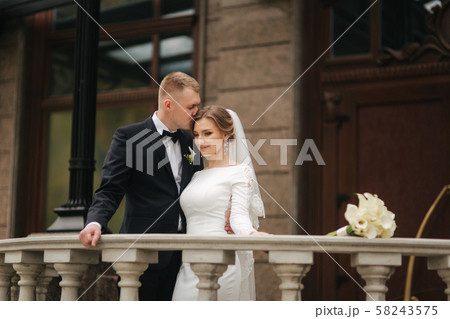 Portrait of beautiful wedding couple stand on the balcony. Stylish bride and groom in autumn weather 58243575