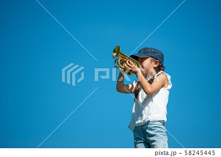 青空の下でトランペットを演奏する女の子の写真素材 青空の下でトランペットを演奏する女の子の写真素材