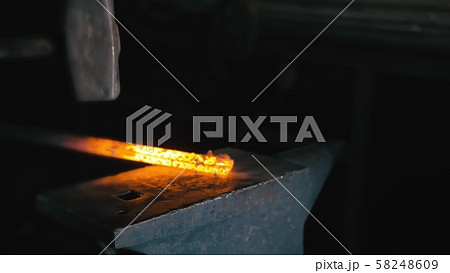 Forge workshop. Smithy manual production. Hands of smith with hammer hit on glowing hot metal, on 58248609
