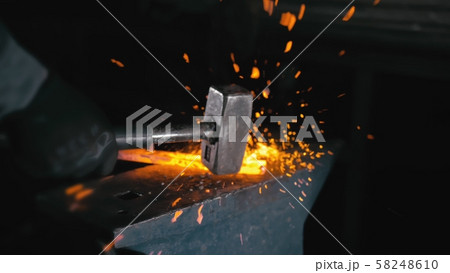 Forge workshop. Smithy manual production. Hands of smith with hammer hit on glowing hot metal, on 58248610