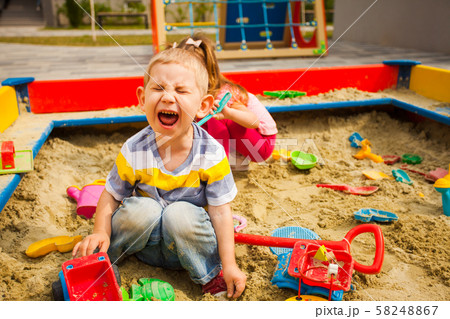 two grubby kids playing in the sandbox 58248867