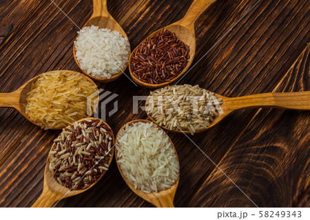 Wooden spoons with different rice types on the wooden background 58249343