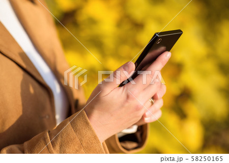Woman using mobile phone outside. Hands holding 58250165