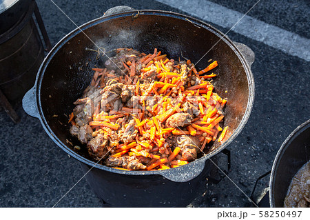 Pieces of meat cooking in a large cauldron with Pieces of meat cooking in a large cauldron with 58250497