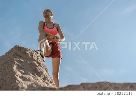 Young concentrated lady staying on rock ledge 58252115