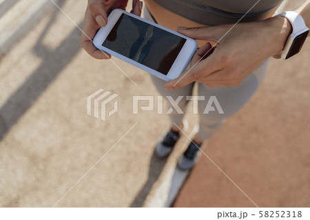 Athletic lady taking photo of road on mobile phone 58252318