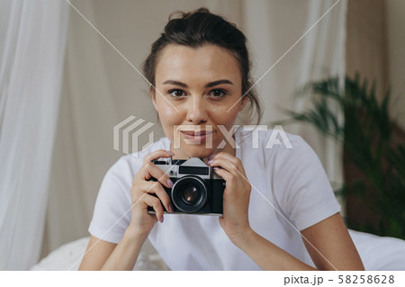 Pretty young woman is holding camera at home Pretty young woman is holding camera at home 58258628
