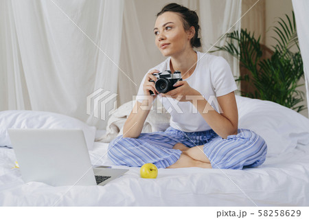 Happy young woman is sitting in bed at home 58258629
