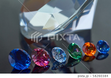 Huge diamond and several chic crystals on a deep black mirror surface, shimmer and sparkle Huge diamond and several chic crystals on a deep black mirror surface, shimmer and sparkle 58260384