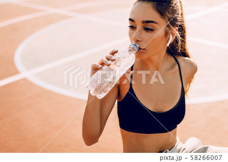 Sporty girl, in top and sweatpants, drinking water 58266007
