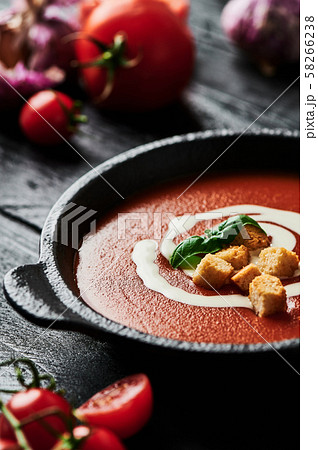 Tomato soup with cream on black wooden background. 58266238